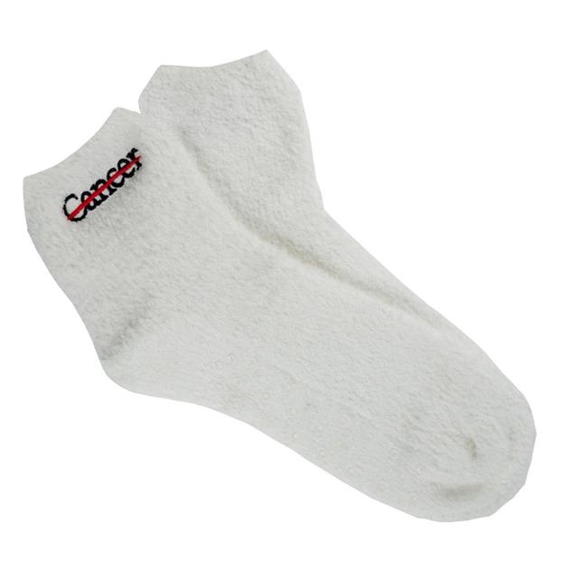 White fuzzy socks with the black cancer strikethrough logo on the side and non-slip grip bottoms.