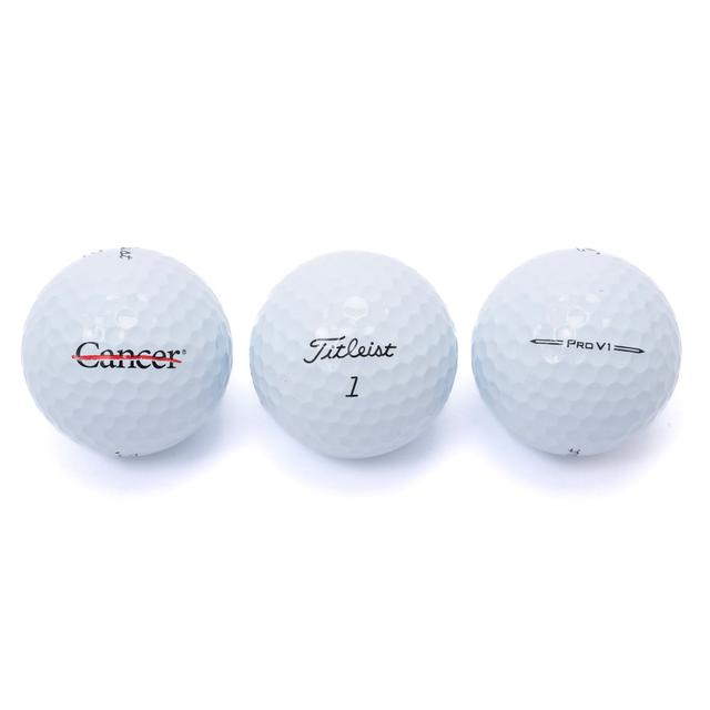 Set of three golf balls, each showcasing the different logos: one featuring the black cancer strikethrough logo, one with the Titleist 1 logo, and one with the Pro V1 logo.